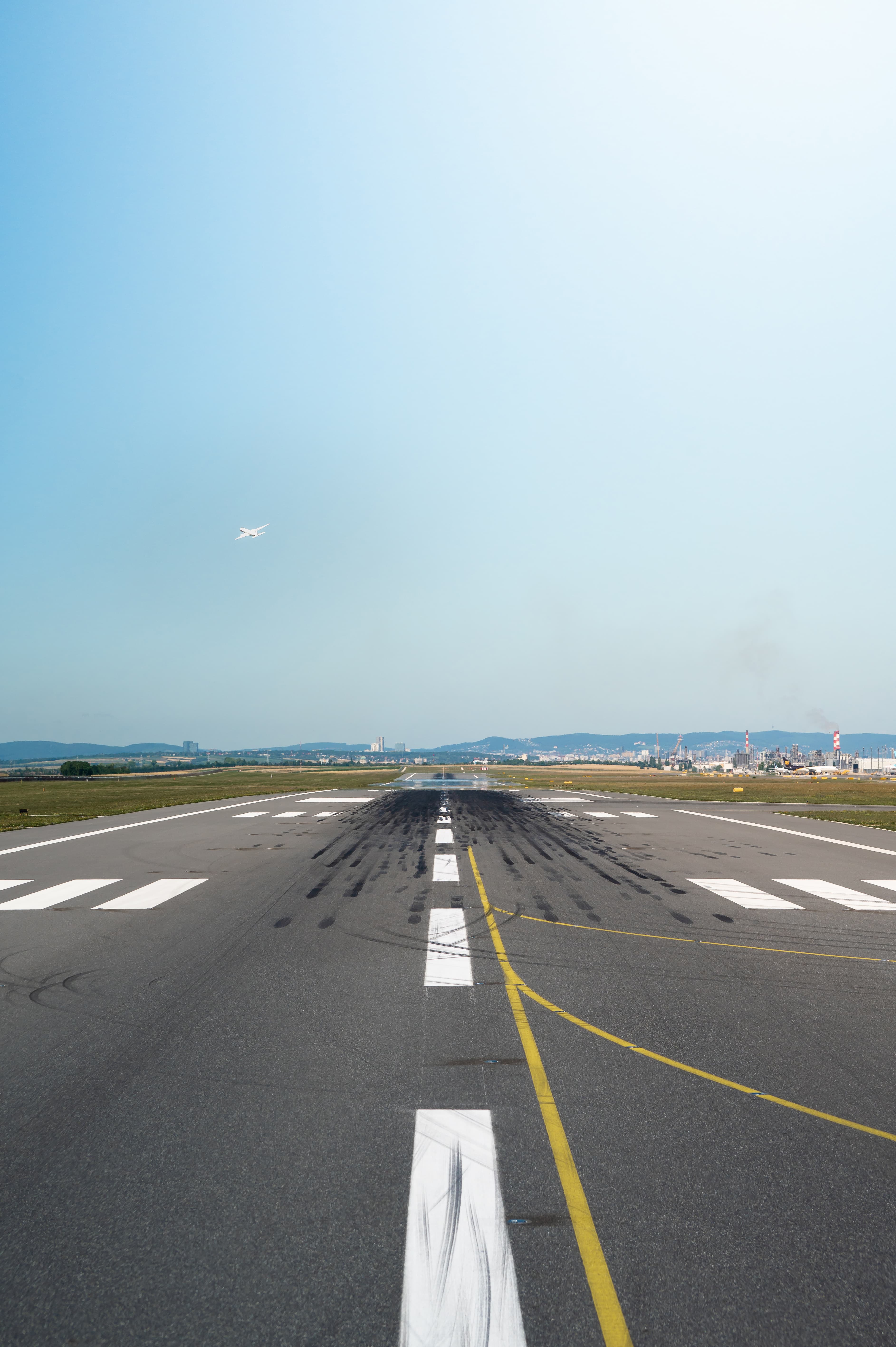 Image of a Runway where a plan is taking off in the distance.