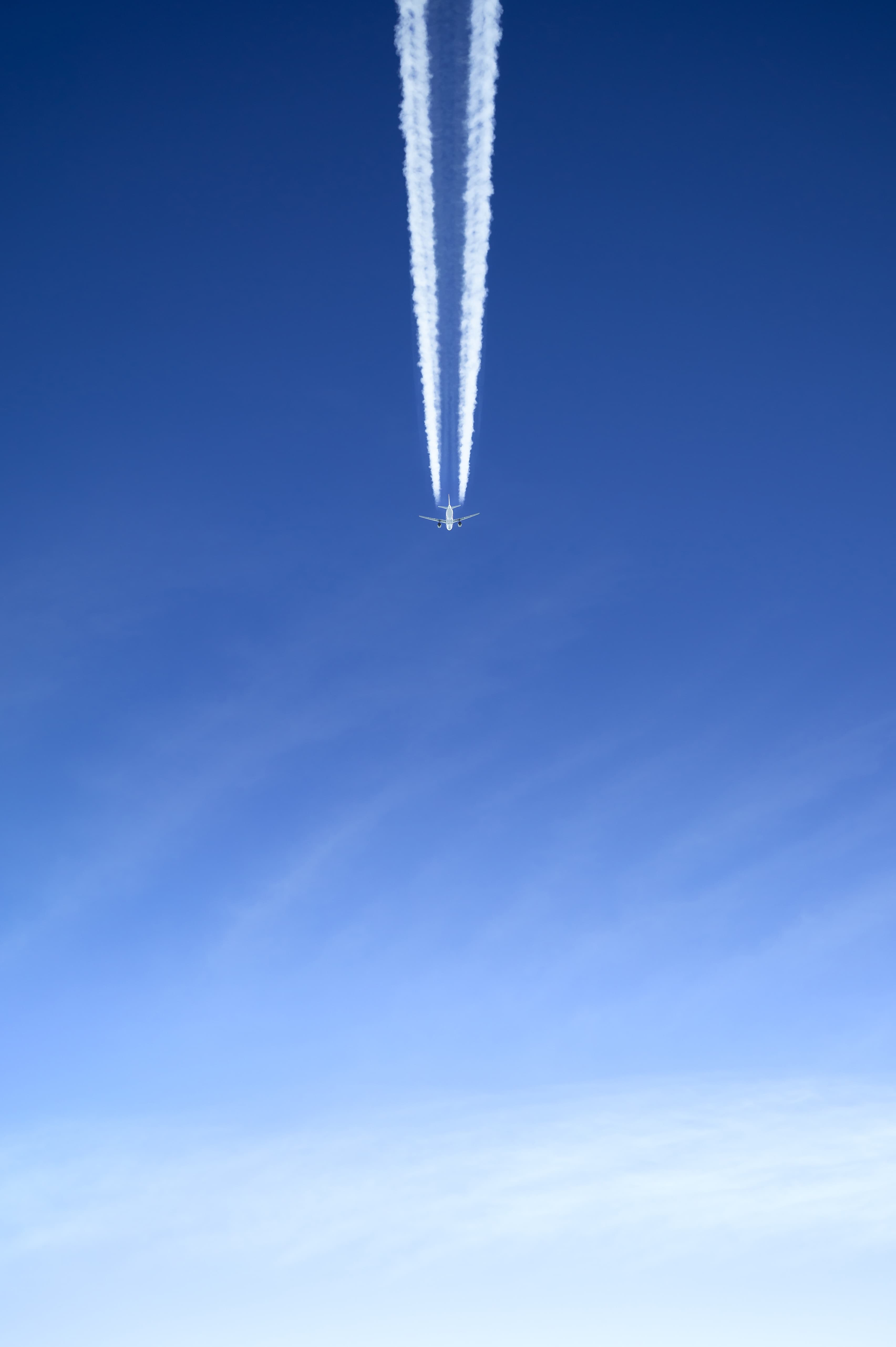 Image of an Airplane in the sky from below with contrails.